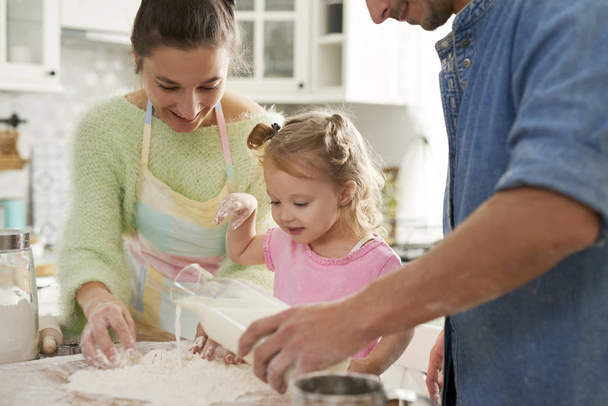 Девочка с родителями готовит еду на кухне
  - Фото, изображение