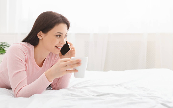 Chica alegre hablando por teléfono, relajarse con café en casa los fines de semana
 - Foto, imagen