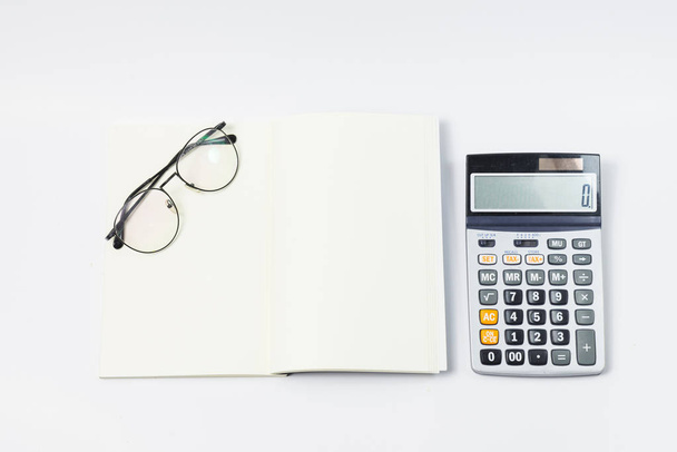 Stationery office equipment or study as Glasses and calculator on blank notebook with center position on white background. Back to school concept. work concept. - Photo, Image