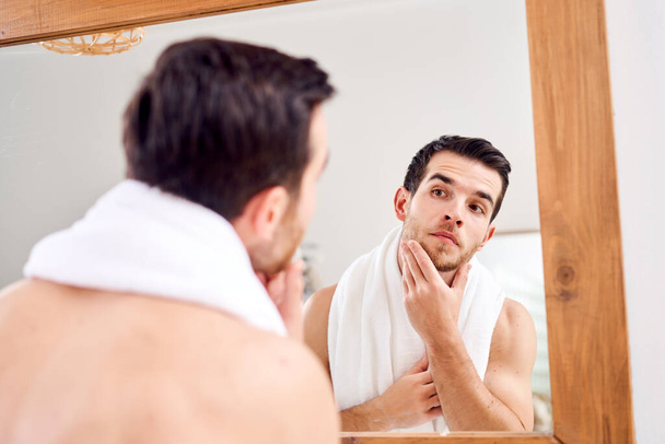 Male with white towel on neck standing near mirror - Photo, Image