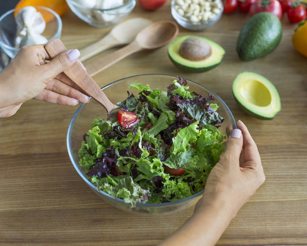 Mains de femme mélangeant salade fraîche de laitue et avocat
 - Photo, image