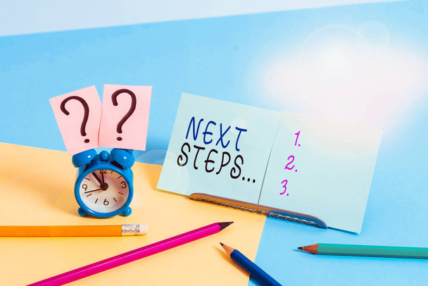 Writing note showing Next Steps. Business concept for something you do or plan after you ve finished something else Mini size alarm clock beside stationary on pastel backdrop - 写真・画像