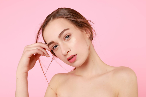 Beautiful young girl touching her perfect skin on pink background. - Фото, зображення