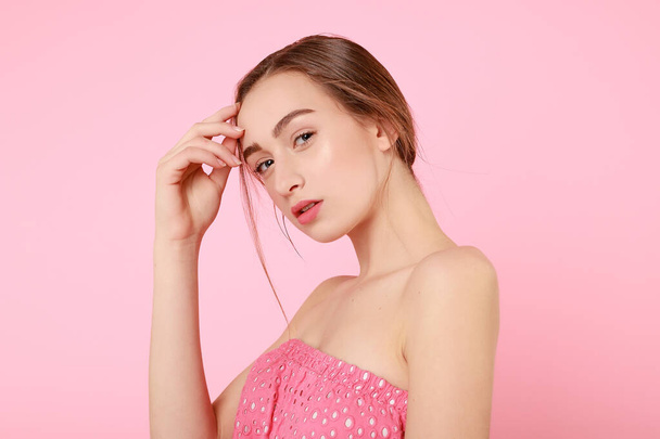 Beautiful young girl touching her perfect skin on pink background. - Photo, image