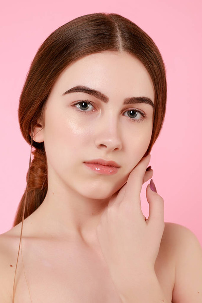 Beautiful young girl touching her perfect skin on pink background. - Foto, afbeelding