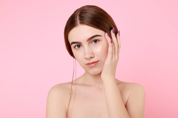 Beautiful young girl touching her perfect skin on pink background. - Foto, Bild