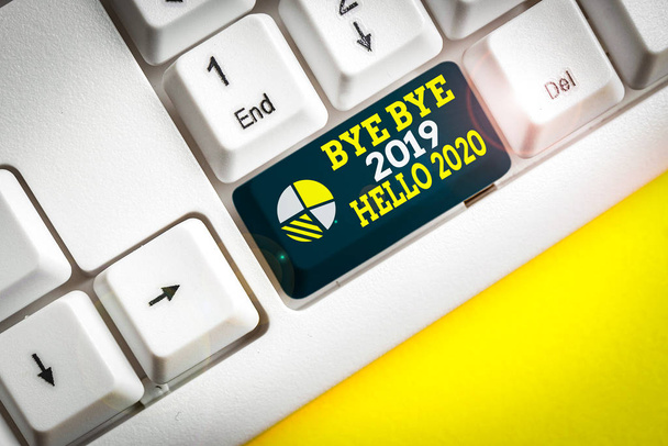 Γραπτή σημείωση που δείχνει αντίο 2019 Γεια σας 2020. Επιχειρηματική έννοια για να αποχαιρετίσει το προηγούμενο έτος και καλωσορίζοντας ένα άλλο καλό λευκό πληκτρολόγιο PC με χαρτί σημείωσης πάνω από το λευκό φόντο - Φωτογραφία, εικόνα