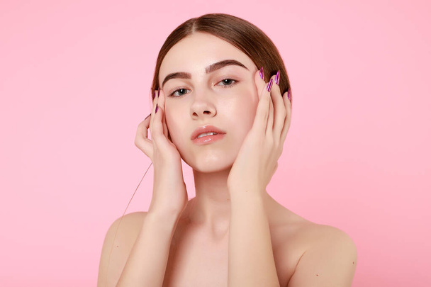 Beautiful young girl touching her perfect skin on pink background. - Fotografie, Obrázek
