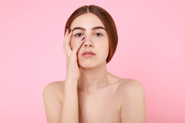 Beautiful young girl touching her perfect skin on pink background. - 写真・画像