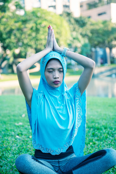 Femme musulmane portant Hijab assis dans un parc de la ville iin Yoga position et méditation - Photo, image