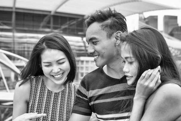 Tres jóvenes asiáticos amigos revisando fotos de la ciudad en el smartph - Foto, Imagen