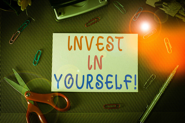 Schrijfbriefje met Invest In Yourself. Business concept voor het leren van nieuwe dingen of materialen waardoor uw lot beter Schaar-en schrijfapparatuur blad boven getextureerde achtergrond - Foto, afbeelding