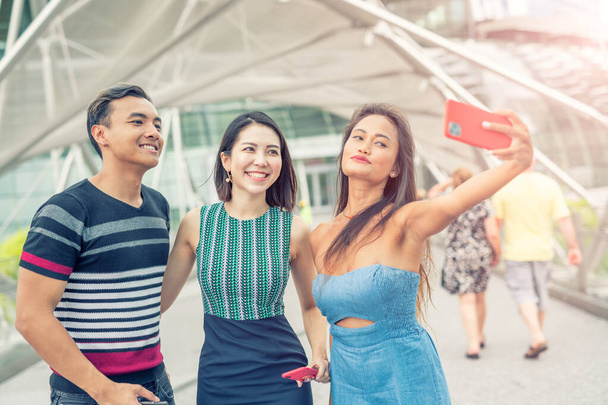 Trzech azjatyckich przyjaciół spacerujących po mieście i robiących sobie selfie. Touri Przewodniczący - Zdjęcie, obraz