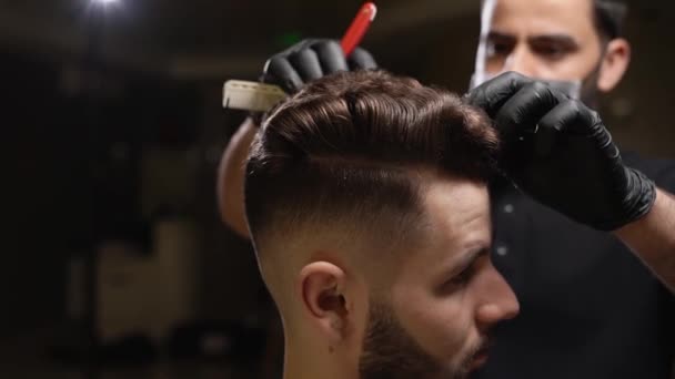 Confident male hairdresser doing trendy haircut for client - Imágenes, Vídeo