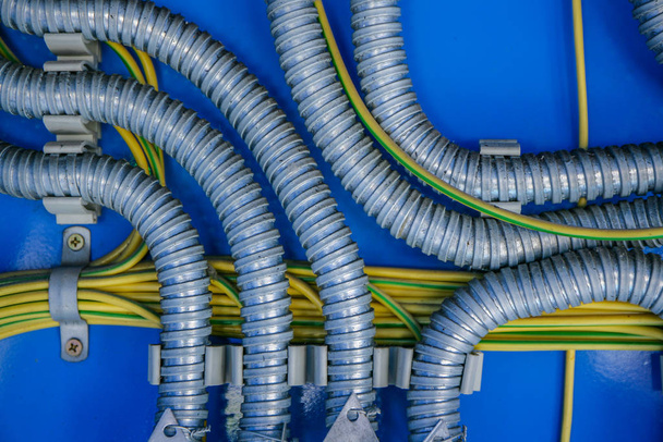 Проводка, распределение проводов в металлическом гофрировании на синем фоне
 - Фото, изображение