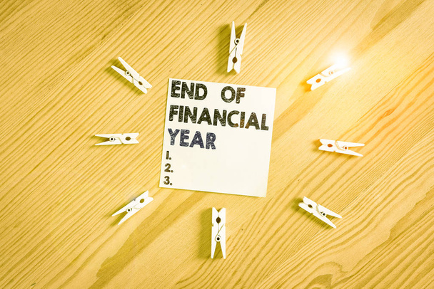 単語書き込みテキスト会計年度の終わり。前年度会計表の見直しと編集を紹介するビジネス写真カラーのクロッシンペーパー空のリマインダ木製の床の背景オフィス - 写真・画像