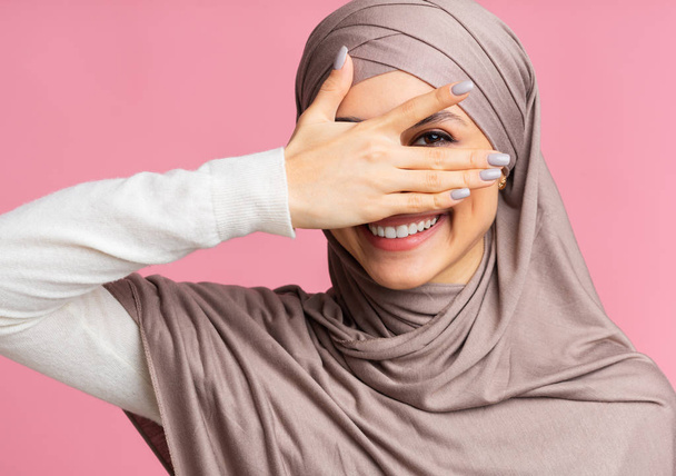 Playful muslim girl peeping through fingers and looking at camera - Фото, изображение
