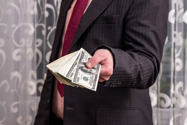 Человек показывает свою прибыль в долларовых банкнотах
 - Фото, изображение