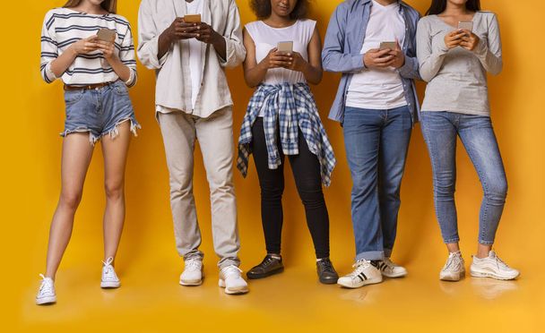 Grupo de amigos adolescentes de raza mixta usando teléfonos inteligentes, recortados
 - Foto, Imagen