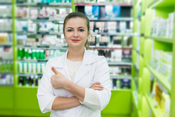 Ελκυστική χαμογελαστή γυναίκα φαρμακοποιός θέτουν σε φαρμακείο - Φωτογραφία, εικόνα