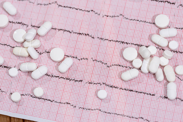 Comprimés blancs dispersés sur cardiogramme gros plan
 - Photo, image