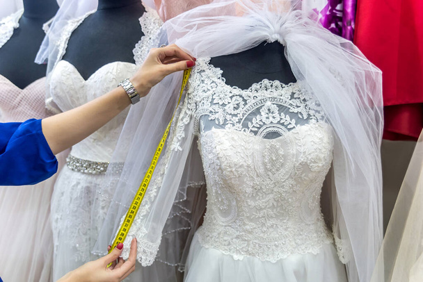 Frauenhände mit Maßband und Brautkleid - Foto, Bild