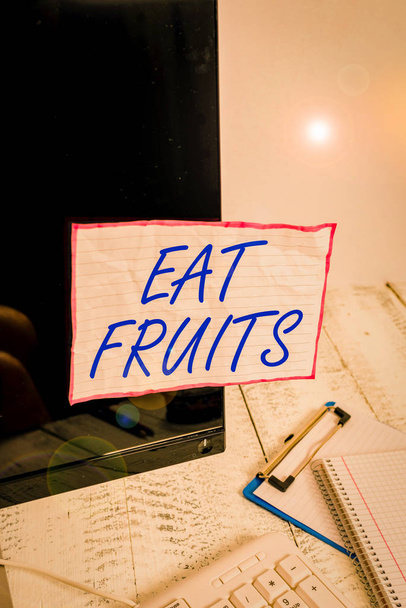 Znak tekstowy "Jedz owoce". Biznes zdjęcie tekst zużywają każdy produkt wzrostu roślin przydatne do huanalysiss lub zwierząt Uwaga papieru przyklejonego do czarnego ekranu komputera w pobliżu klawiatury i stacjonarne - Zdjęcie, obraz
