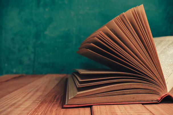 Cerrar hermoso libro viejo abierto sobre una mesa de madera roja. Fondo de pared verde
. - Foto, imagen