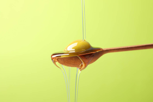 Wooden spoon with olive and pouring olive oil on green backgroun - Foto, Imagem