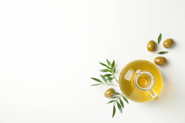 Jug with olive oil, olives and leaves on white background, top v - Foto, imagen