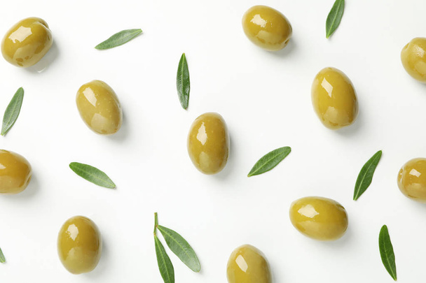 Green olives and leaves on white background, top view - 写真・画像