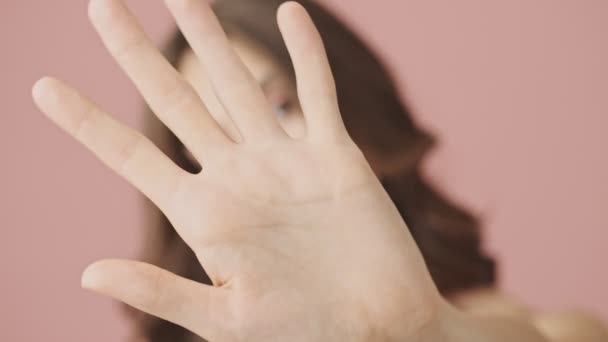 Vista de cerca de la joven mujer semidesnuda está agitando su mano frente a la cámara aislada sobre el fondo rosa
 - Metraje, vídeo