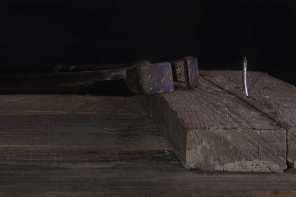 Один гострий металевий цвях у старій дошці та іржаві ножиці на дерев'яному фоні. Низький ключ
 - Фото, зображення
