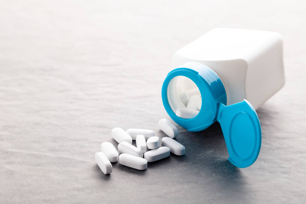 Léková medicína tablety, pilulky, kapsle, léky na šedém pozadí v bílé a modré plastové nádobě. Pilulka láhev pozadí použití v prezentacích, vzdělávací manuály, design, 3D ilustrace - Fotografie, Obrázek