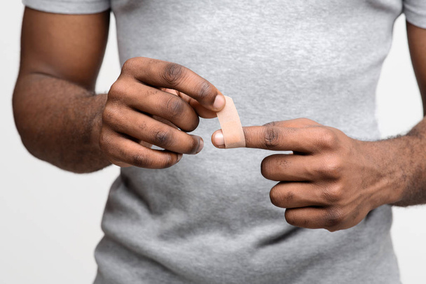 Közelkép egy férfiról, aki ragasztószalagot használ a sérült ujján. - Fotó, kép