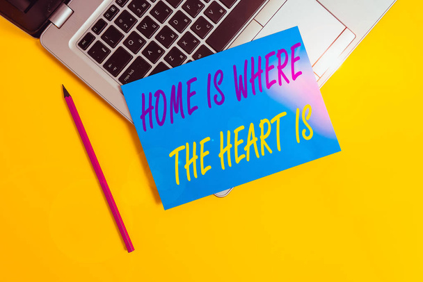 Conceptual hand writing showing Home Is Where The Heart Is. Concept meaning Your house is where you feel comfortable and happy Metallic laptop small paper sheet pencil colored background - Photo, Image