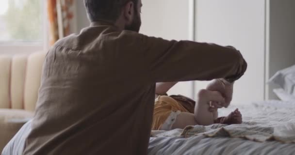 Father changing diapers of baby in bedroom - Felvétel, videó