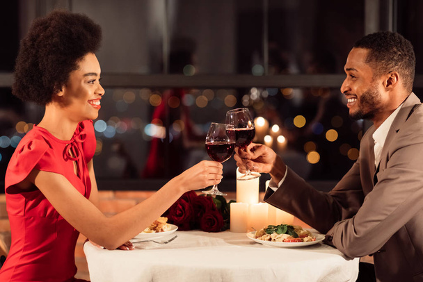 Joyeux couple clinking verres à boire du vin rouge assis dans le restaurant
 - Photo, image