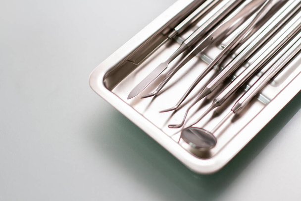 стоматологічні медичні інструменти в металевому лотку на скляному столі
 - Фото, зображення