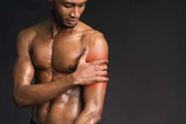 Hombre afro guapo sin camisa que sufre de dolor en el brazo
 - Foto, imagen