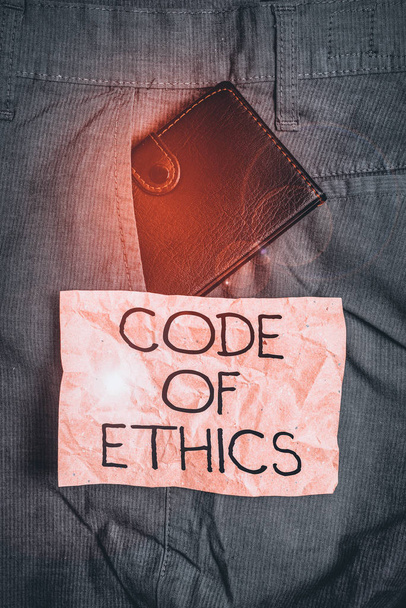 Word writing text Code Of Ethics. Business photo showcasing basic guide for professional conduct and imposes duties Small little wallet inside man trousers front pocket near notation paper - Photo, Image