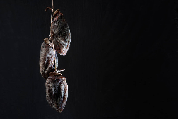 whole fruits of dried persimmons in a bunch on a black background - Photo, image