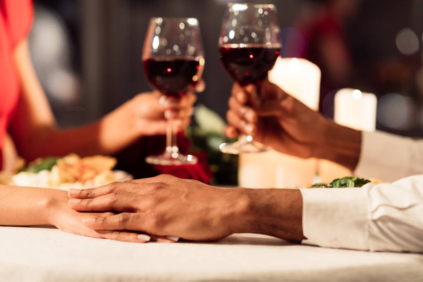 Pár kéz a kézben és pirítóssal ünnepli Valentin étteremben, kivágott - Fotó, kép