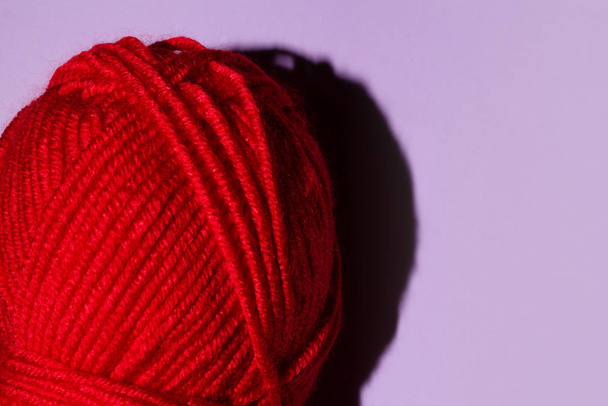 Espinha vermelha de fio para tricotar em um fundo roxo, espaço de cópia. macro
 - Foto, Imagem
