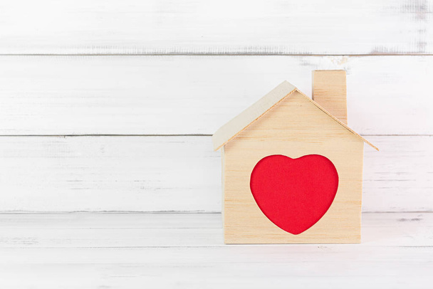 Casa de madera con contorno de corazón rojo en casa sobre bac de madera blanca
 - Foto, Imagen