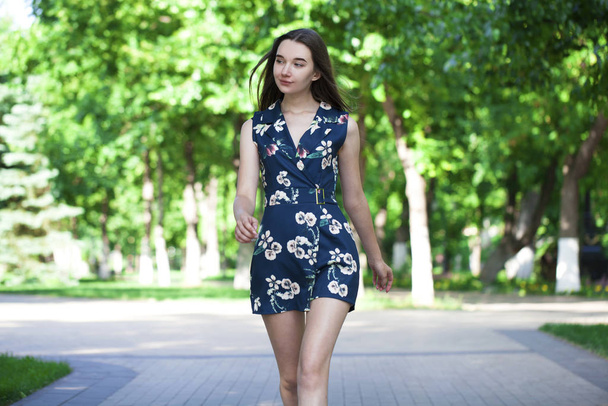 Young beautiful woman in a blue short dress walking on the road - Φωτογραφία, εικόνα