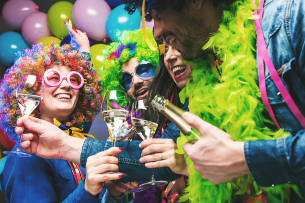 Szczęśliwi młodzi ludzie pijący szampana i świętujący karnawał lub Nowy Rok  - Zdjęcie, obraz