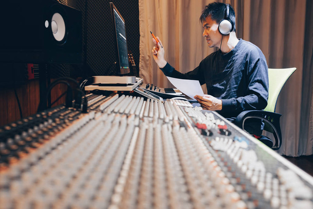 asian young male professional music producer, sound engineer, composer, arranger working in home recording studio. post production and broadcasting concept - 写真・画像