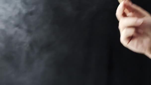 Κοντινό γυναικείο χέρι που κρατάει και καπνίζει μαριχουάνα σε μαύρο φόντο. Η κάνναβη είναι μια έννοια της φυτικής ιατρικής - Πλάνα, βίντεο