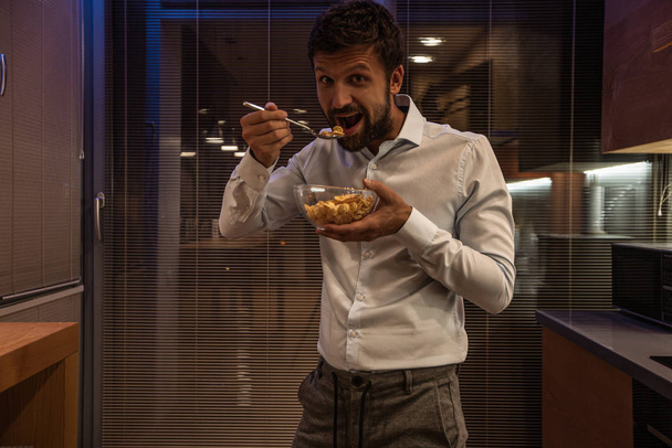 uomo barbuto mangiare cereali da ciotola di vetro in cucina
  - Foto, immagini